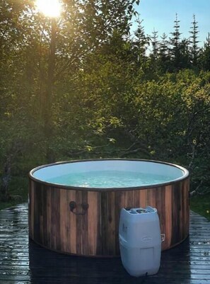 Un jacuzzi en una terraza de madera con un entorno natural.