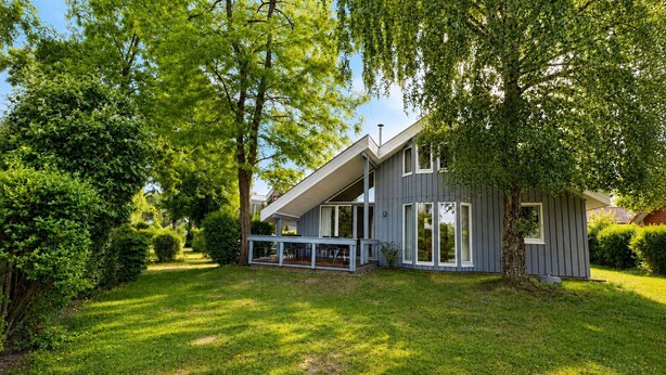 A modern house with a sloped roof, large windows, and a covered porch. - Skandinavisches Ferienhaus mit Privatsauna im Hafendorf Muritz (Mirow)