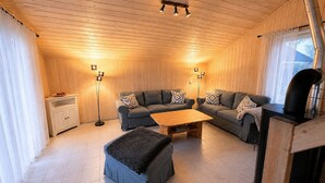 A cozy living room with a sofa set, a coffee table, and a fireplace. - Skandinavisches Ferienhaus mit Privatsauna im Hafendorf Muritz (Mirow)