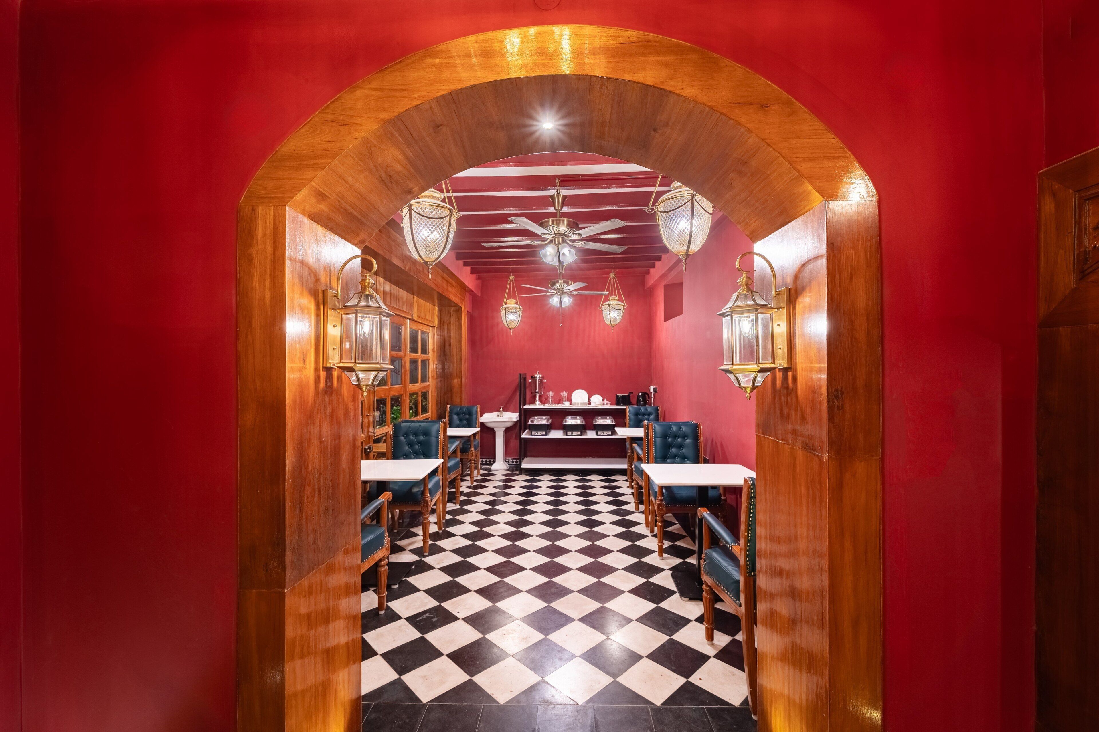 A restaurant with a checkered floor, wooden arches, and blue upholstered chairs.