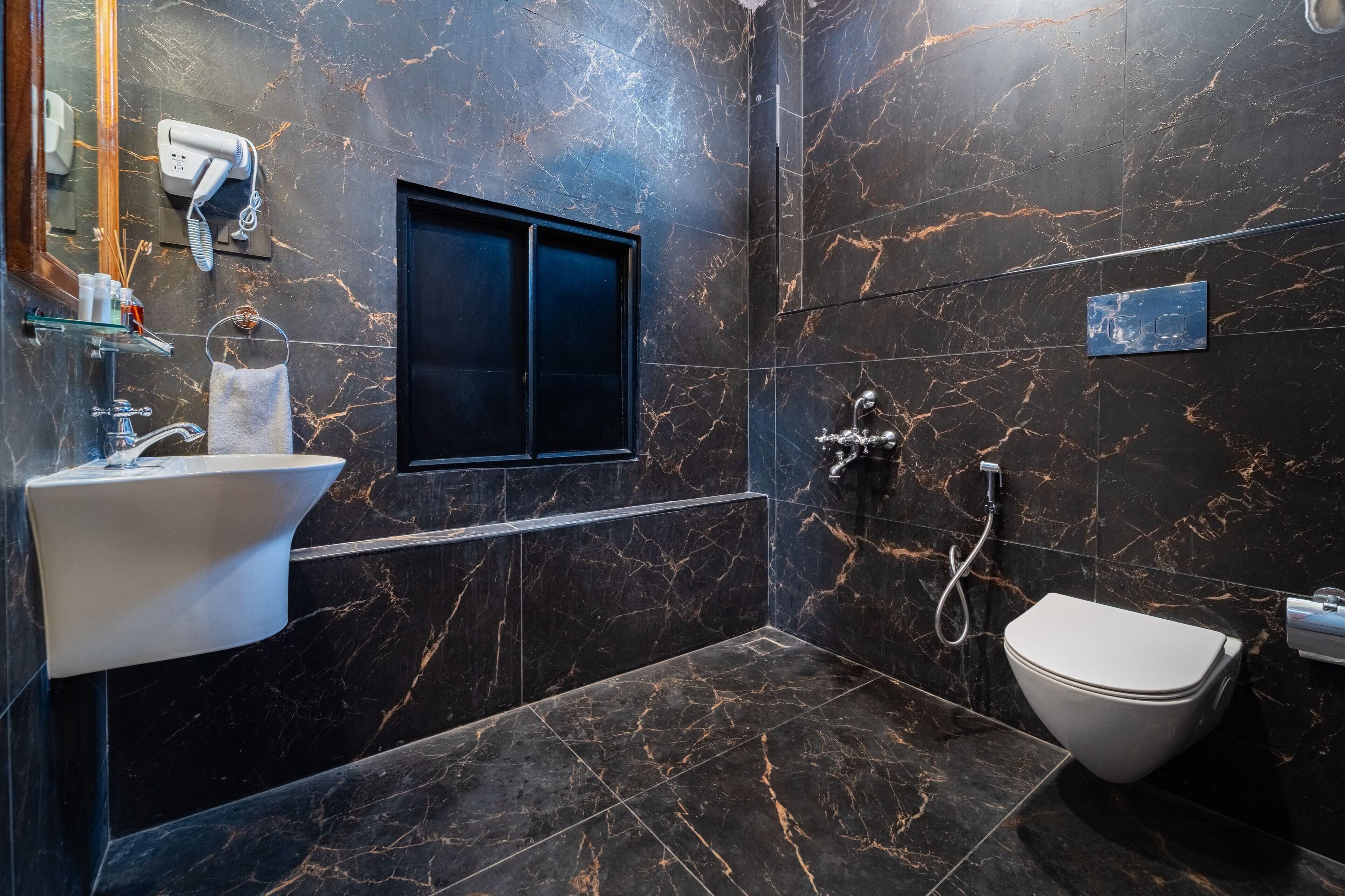 Une salle de bain moderne avec un sol en marbre, un lavabo blanc, des toilettes et un espace douche.