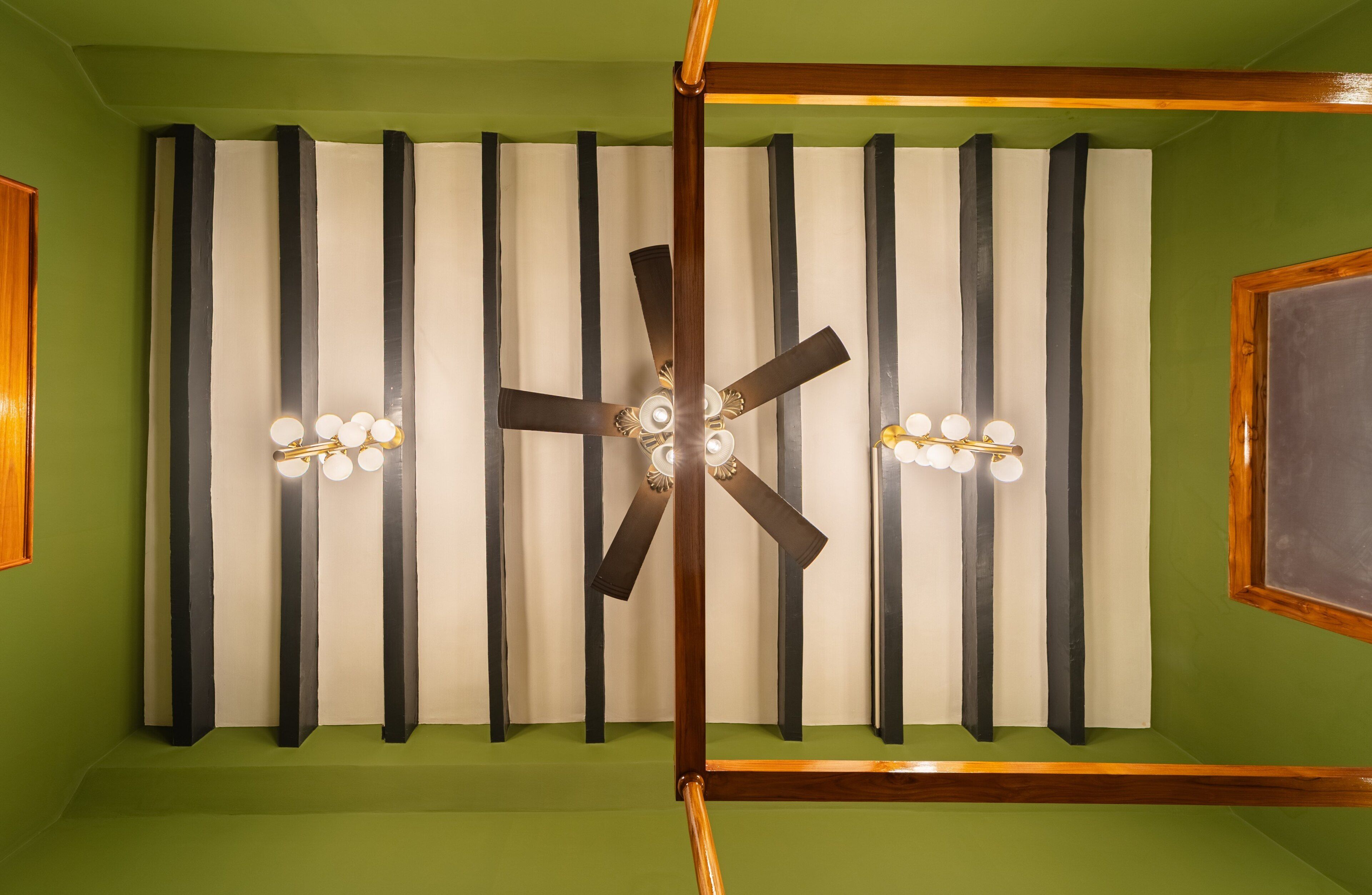 Une pièce dotée d’un ventilateur de plafond, d’une structure en bois et d’un mur vert.