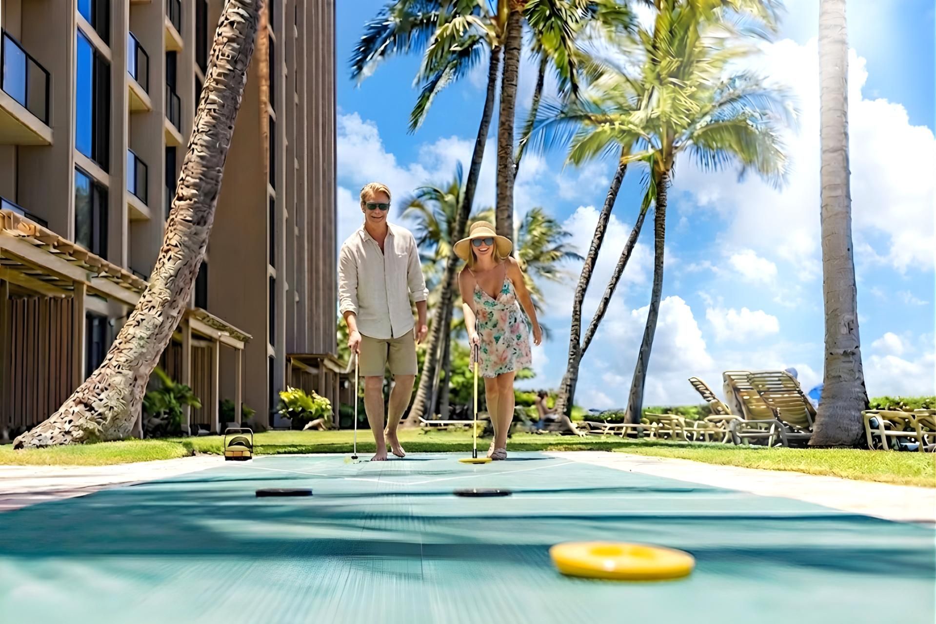 A couple playing croquet on a deck with palm trees and a pool in the background.