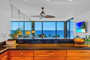 A modern kitchen with a large island, a ceiling fan, and a view of the ocean. - Mahana | 4 Oceanfront Villas, Sleeps 14 | Car Incl. w/ 6+ Nights | ML-4211 by KBM (Lahaina)