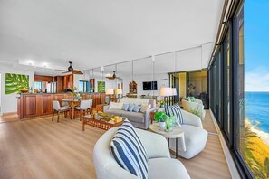 Ein modernes Wohnzimmer mit Essbereich, Küche und großen Fenstern mit Meerblick.