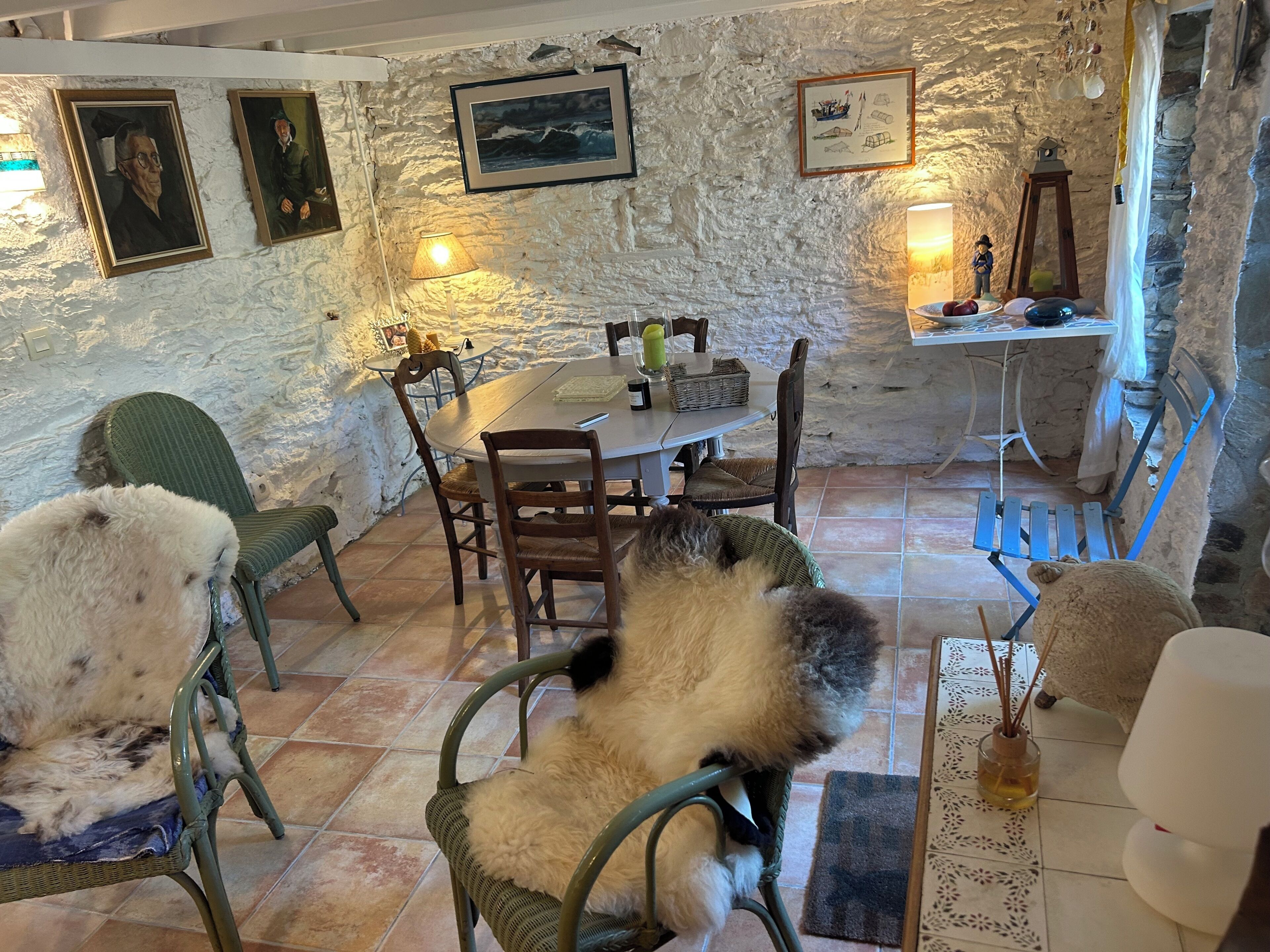A rustic dining area with stone walls, wooden furniture, and framed artwork.