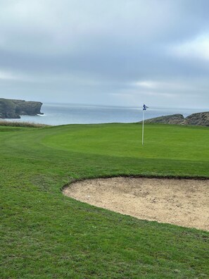 A golf course with a flagstick, a sand bunker, and a view of the sea. - House located 700 meters from Grands-Sables Beach, accessible via a country lane and featuring an enclosed garden (Locmaria)