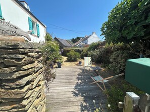 A wooden pathway leading to a house with a stone wall on one side and a green awning on the other. - House located 700 meters from Grands-Sables Beach, accessible via a country lane and featuring an enclosed garden (Locmaria)