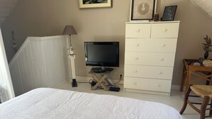 Un dormitorio con cama, televisión, cómoda y silla.