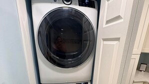 Uma lavanderia compacta com máquina de lavar e secadora empilhadas, uma porta e um interruptor de luz na parede.