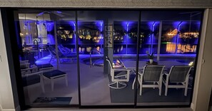 En modern inredning med ett poolområde, solstolar och utsikt över stadsbilden på natten.