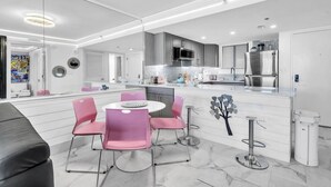 A modern kitchen with a central island, pink chairs, and a marble floor. - Sundestin 1014 1 Bedroom Condo (Destin)