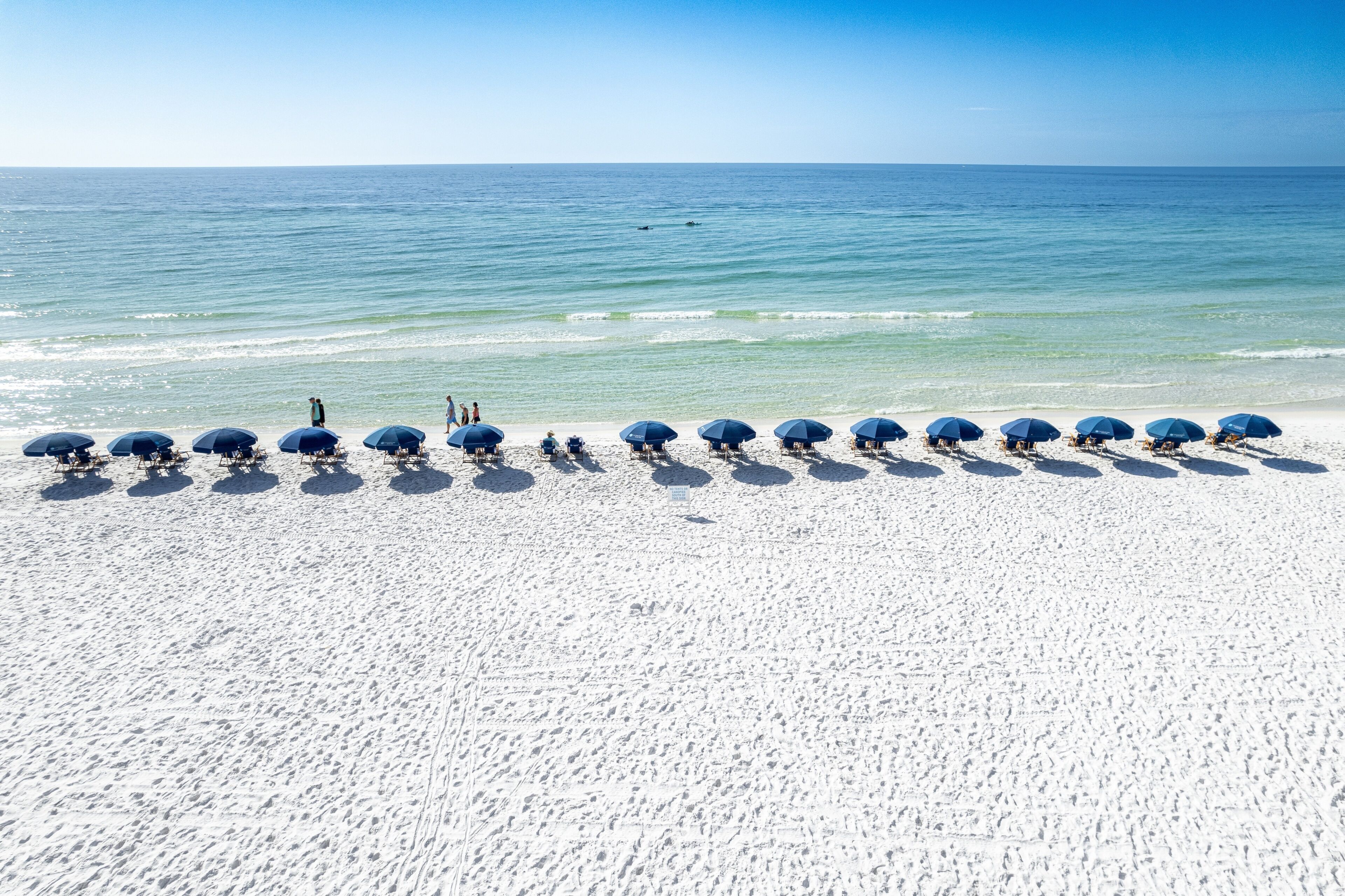 Ein Strand mit Reihen von Sonnenschirmen und Menschen.