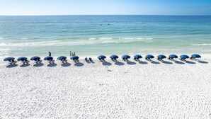 Een strand met rijen parasols en mensen.