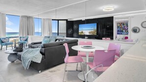 Een moderne woonkamer met een grote televisie, een zithoek en uitzicht op het strand.