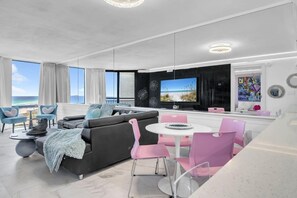 Un salon moderne doté d’un grand téléviseur, d’un coin salon et offrant une vue sur la plage.