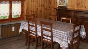 A dining area with a wooden ceiling, a table with chairs, and a window with curtains. - Soffio di Miele, the perfect place to visit Valtournenche (Pâquier)
