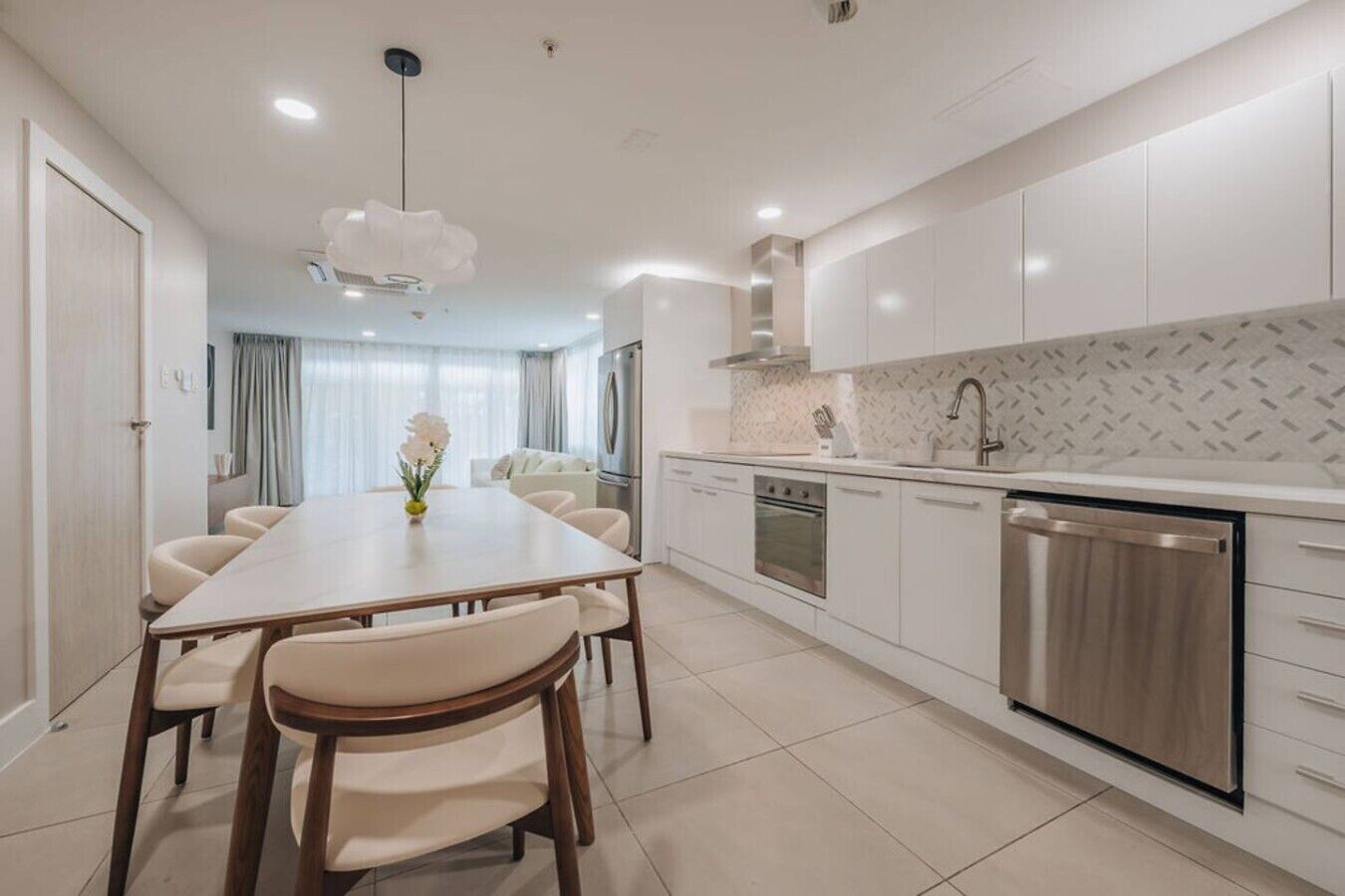 A modern kitchen with a dining area, stainless steel appliances, and a tiled backsplash.