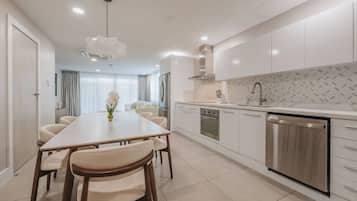 A modern kitchen with a dining area, stainless steel appliances, and a tiled backsplash.