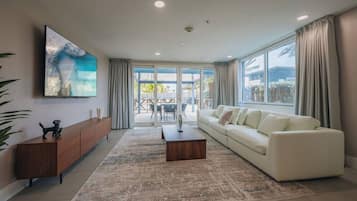 A modern living room with a sofa, coffee table, and a TV mounted on the wall.