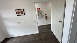 Ein Korridor mit einem Brandmelder, einem Feuerlöscher und einem gerahmten Bild an der Wand.
