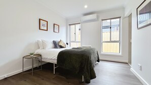 A bedroom with a bed, bedside tables, a window, and an air conditioning unit. - 2024Built/AC & Bath each Room/Study/TownCentre/SDA (Werribee)