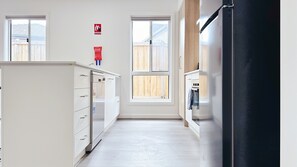 Eine Küche mit Kühlschrank, Herd und Schränken, einem Schild für Feuerdecken sowie einem Fenster mit Blick auf einen Holzzaun.
