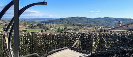 A hammock chair on a balcony overlooking a vineyard.