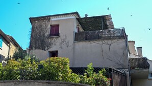 A building with a balcony, a window with red shutters, and a clear blue sky with birds in the background. - Artist's home in Pierrevert, Provence, with a 20-square-meter terrace offering panoramic views (Pierrevert)