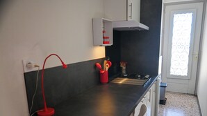 A kitchen with a black countertop, a red lamp, and a window with decorative iron bars. - Artist's home in Pierrevert, Provence, with a 20-square-meter terrace offering panoramic views (Pierrevert)