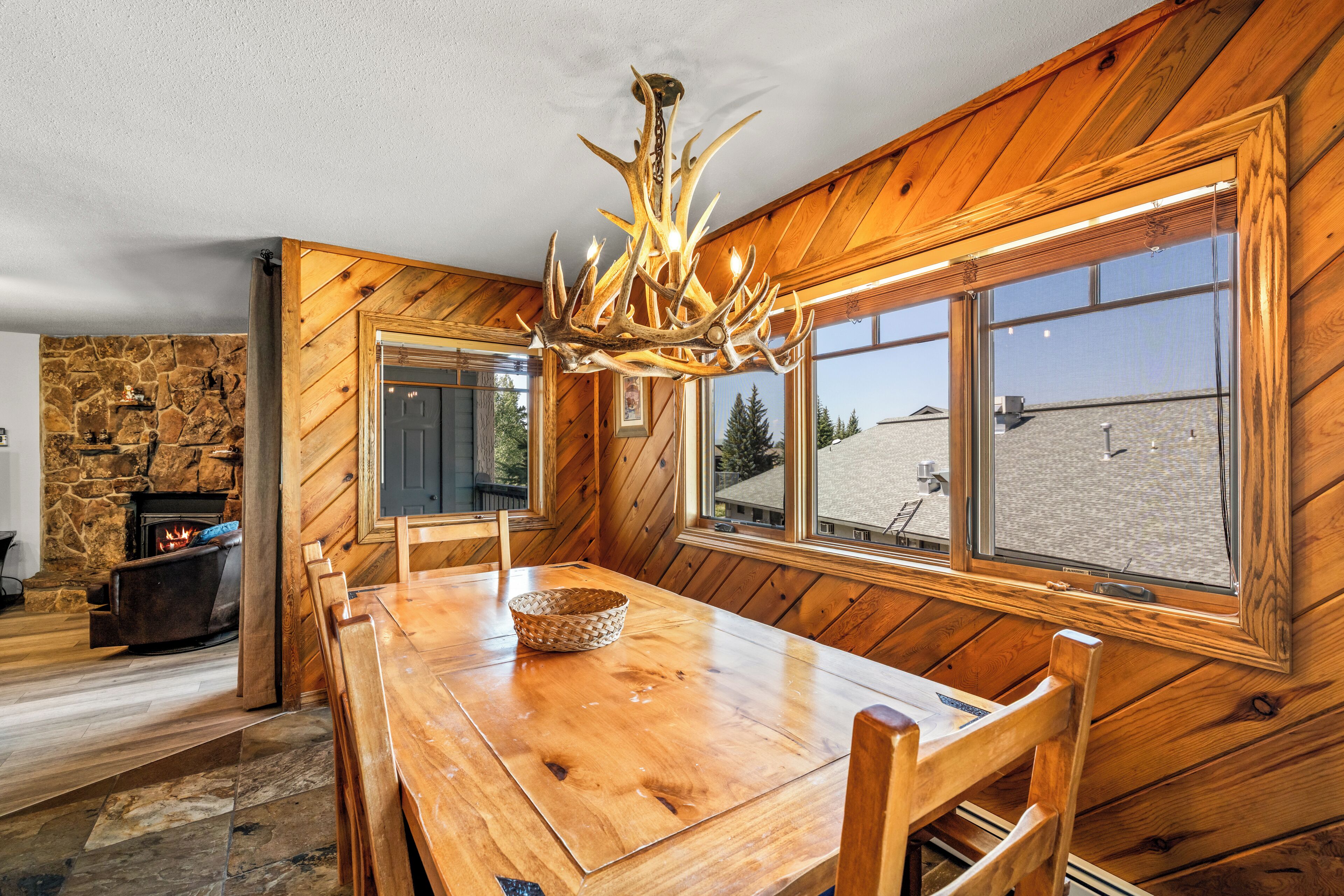 Un interior de madera con una mesa de comedor, sillas, una chimenea y un ventanal con vistas.
