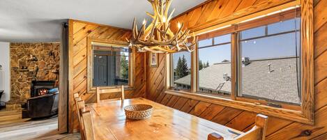 Un interior de madera con una mesa de comedor, sillas, una chimenea y un ventanal con vistas.