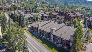 Un hôtel moderne à plusieurs étages, doté d’une cour intérieure et entouré d’une végétation luxuriante, avec une chaîne de montagnes en toile de fond.
