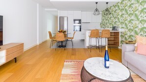 A modern living room with a sofa, a coffee table, and a dining area with chairs and a kitchen in the background. - Apartment in Las Palmas Near Playa Alcaravaneras (Las Palmas de Gran Canaria)