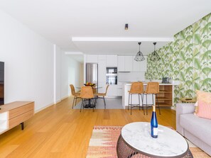 A modern living room with a sofa, a coffee table, and a dining area with chairs and a kitchen in the background. - Apartment in Las Palmas Near Playa Alcaravaneras (Las Palmas de Gran Canaria)