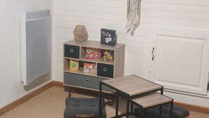 Ein Zimmer mit Schlafkoje, einem kleinen Tisch, einem Bücherregal mit Gesellschaftsspielen, einem Traumfänger und einem Heizkörper.