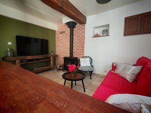 A living room with a TV, a brick wall, a red sofa, and a wooden table. - Mountain home, perfect for families (Aste-Béon)