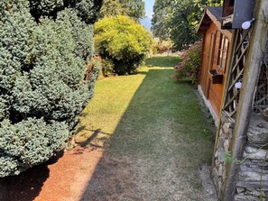 A garden pathway leading to a wooden structure with a window and a light fixture. - Mountain home, perfect for families (Aste-Béon)