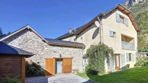 Ein zweistöckiges Steinhaus mit einer Steinaußenseite, Holzläden und einem Balkon.