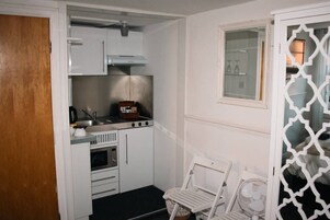 Una cocina compacta con estufa, horno y armarios blancos.