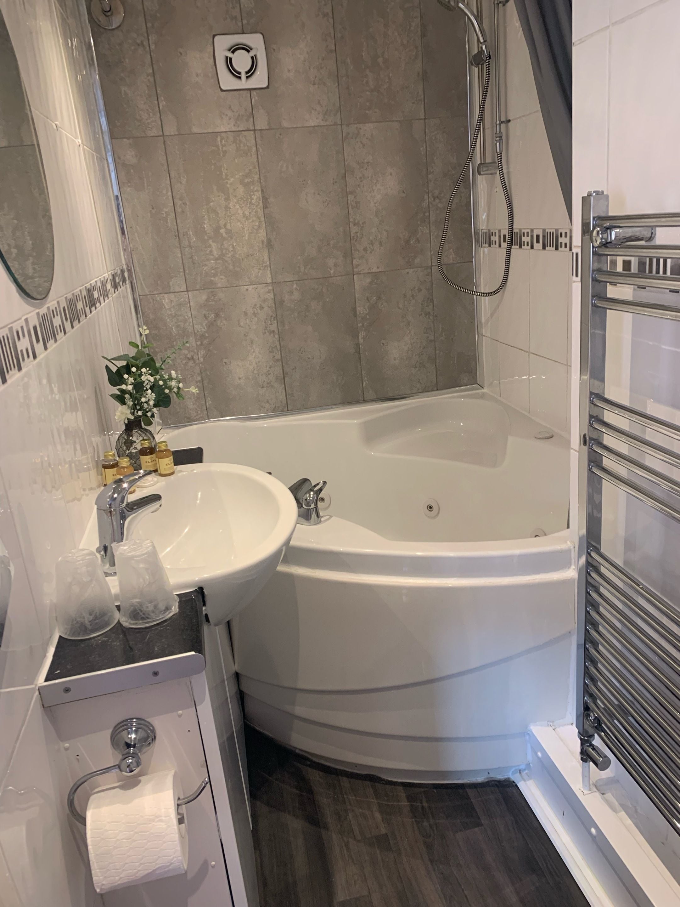 Un baño moderno con una bañera en esquina, un lavabo y una ducha.
