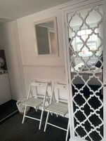Una habitación con una puerta blanca de diseño geométrico, un banco blanco con un cesto y un espejo en la pared.