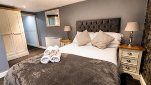 A hotel room with a bed, two bedside tables, a wardrobe, and a mirror. - The Lobster Pots - Bawtry (Bawtry)