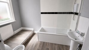 A bathroom with a bathtub, a sink, and a window. - The Lobster Pots - Bawtry (Bawtry)