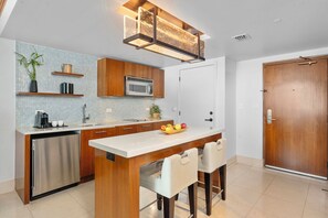 A modern kitchen with a central island, stainless steel appliances, and a wooden door. - Private Residence at Carillon Resort - 910 (Miami Beach)