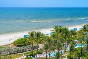 A beach resort with a pool, palm trees, and a view of the ocean. - Private Residence at Carillon Resort - 910 (Miami Beach)