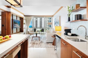 A modern kitchen with a large window, a dining area, and a living room with a view of the city. - Private Residence at Carillon Resort - 910 (Miami Beach)