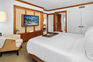 A hotel room with a bed, a TV mounted on a wooden panel, a desk with a chair, and a wardrobe. - Private Residence at Carillon Resort - 910 (Miami Beach)
