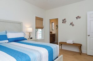 Ein Schlafzimmer mit Bett, Nachttisch, Lampe, Bank und Wanddekorationen.