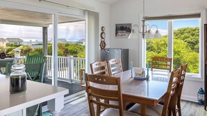 Un comedor con mesa y sillas, refrigerador y vista a zonas verdes y casas.